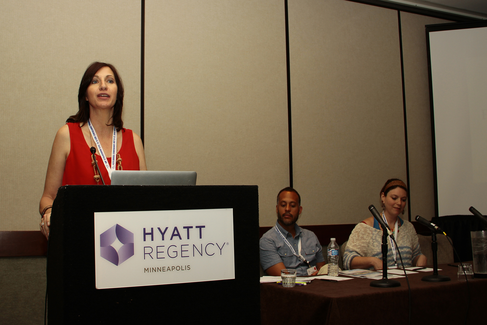 photo of Lorette behind the podium speaking on Art Therapy